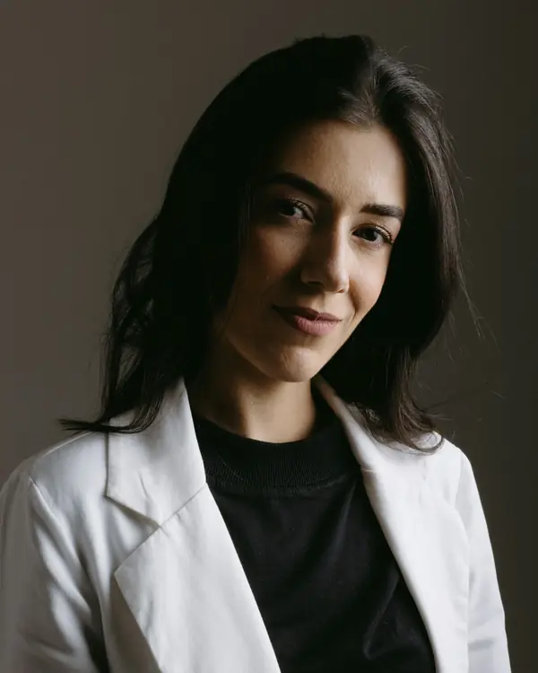 Portrait of a woman doctor in a white jacket against a dark wall