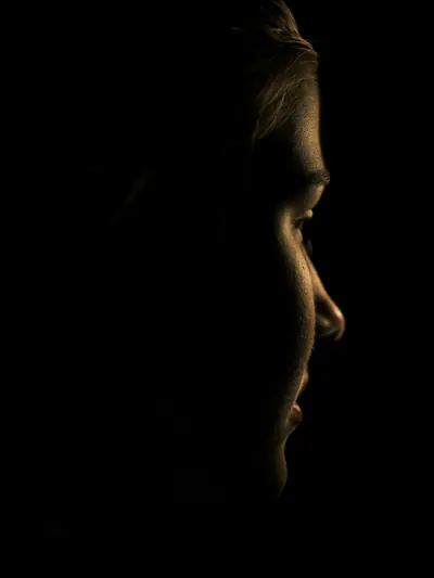 A face in profile, only the jawline and cheekbone touched by light