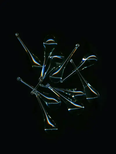 Glass pipettes scattered on a black surface, catching the light