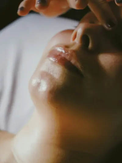 A client receiving a facial massage, warm light across her chin and lips