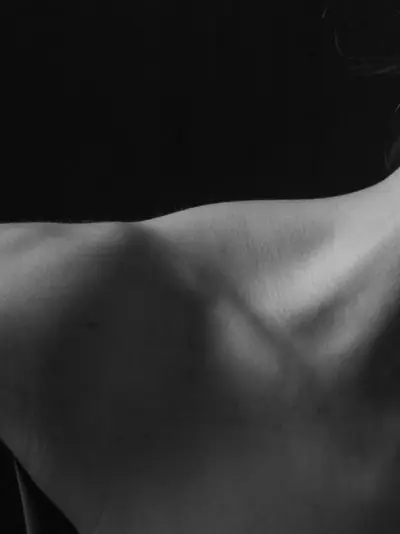 Black-and-white study of a shoulder and upper arm against a dark background